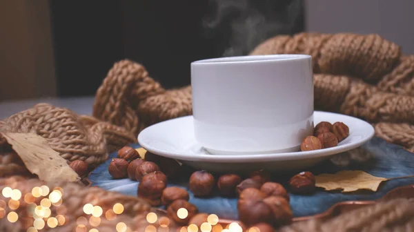 Autumn background with coffee, knitted scarf, pumpkin. Autumn coffee, dry leaves. Season October, November.