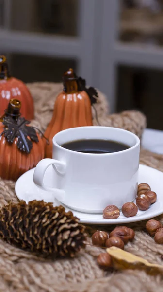 Autumn background with coffee, knitted scarf, pumpkin. Autumn coffee, dry leaves. Season October, November.