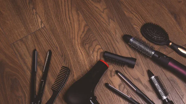 Hairdressing tools on a wooden background. Combs and hair dryer, hair straightener. Long hair curls. Extension hair care.