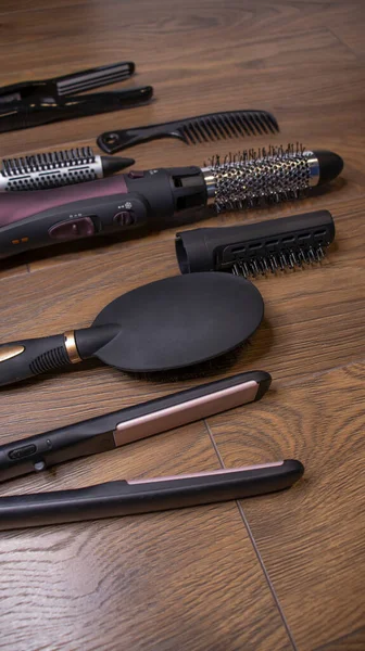 Hairdressing tools on a wooden background. Combs and hair dryer, hair straightener. Long hair curls. Extension hair care.