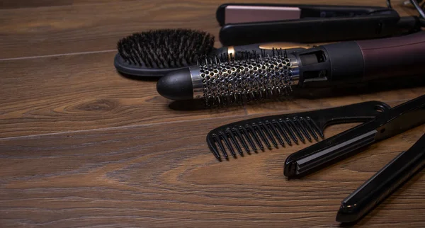 Hairdressing tools on a wooden background. Combs and hair dryer, hair straightener. Long hair curls. Extension hair care.
