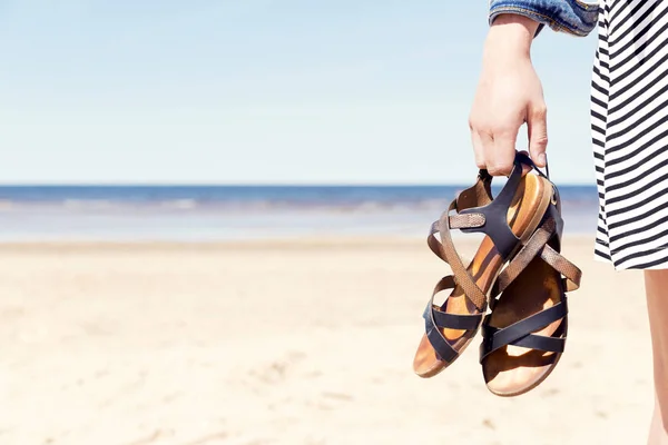 在阳光灿烂的夏日 海滩上拿着凉鞋的女人 — 图库照片