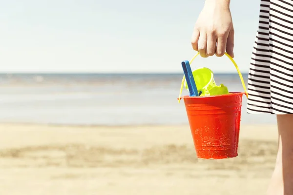 妇女抱着水桶与儿童沙滩玩具 铲和铲在一个晴朗的日子 — 图库照片