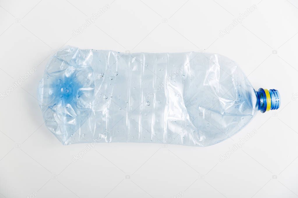 Crushed blue plastic bottle on white background. pollution concept
