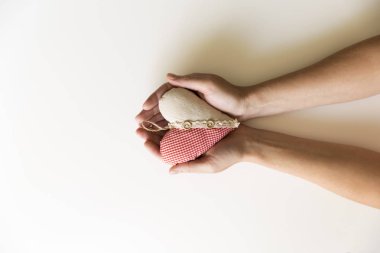 Beyaz zemin üzerine kırmızı kumaş kalp tutan eller. Aşk ve ilişki kavramı. Konsept almak ve vermek