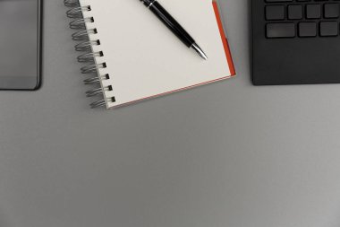 Modern gri ofis resepsiyon masası smartphone, kalem ve klavye ile boş defter sayfası ile. Çalışma, yazma kavramı
