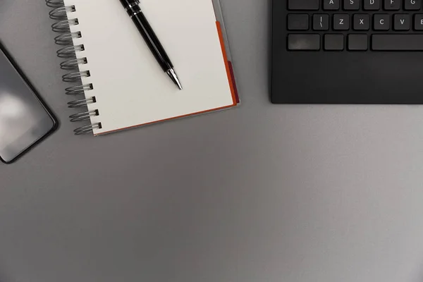 现代灰色办公桌带智能手机 空白笔记本页面 钢笔和键盘 写作理念 — 图库照片