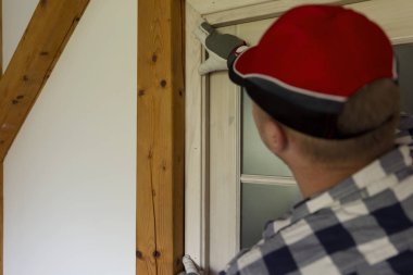 Ev tadilatı. Kapı için ahşap levha takan bir tamirci.