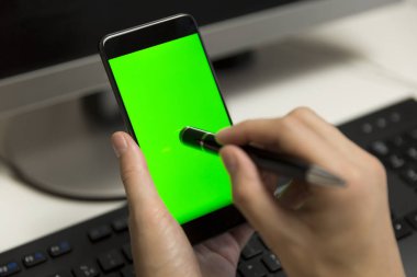 Kadınların elleri kalem için dokunmatik ekran ile telefon ekran dokunur. Hareket eden telefon ile yeşil bir ekran.