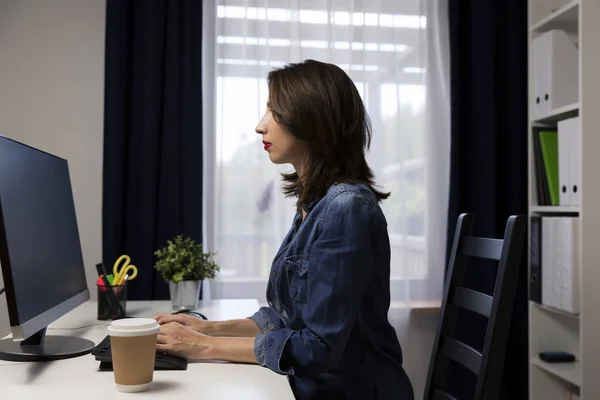坐在电脑旁边的漂亮女人在工作 旁边的咖啡杯 — 图库照片