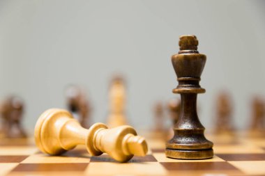 İki yan muzaffer koyu ahşap Kral dibinde yatan ışık king ile satranç taşları bir satranç tahtası üzerinde Kral