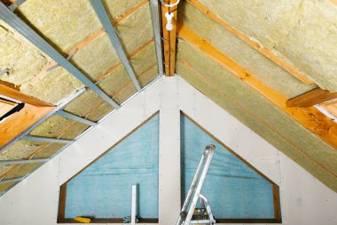 Adam termal çatı yalıtım tabakasını mineral yün paneller kullanarak kuruyor. Tavan arası yenileme ve yalıtım konsepti