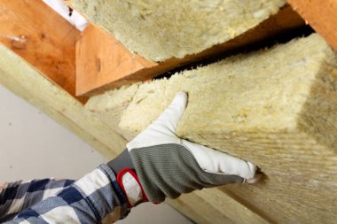 Adam termal çatı yalıtım tabakasını mineral yün paneller kullanarak kuruyor. Tavan arası yenileme ve yalıtım konsepti