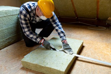 Adam termal çatı yalıtım tabakasını mineral yün paneller kullanarak kuruyor. Tavan arası yenileme ve yalıtım konsepti