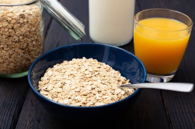 Kase ve doku ile koyu ahşap masa üzerinde taze portakal suyu sağlıklı kahvaltı gevreği yulaf haddelenmiş yulaf, pul