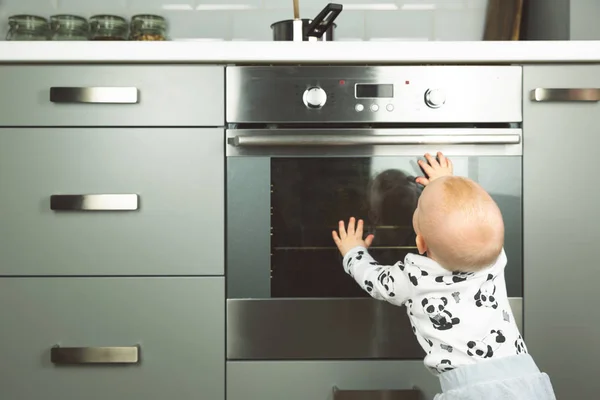 Niño jugando con estufa eléctrica en la cocina. Bebé sa —  Fotos de Stock