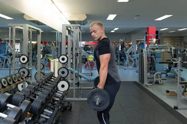 Young man doing the exercises on biceps lifting barbell for good