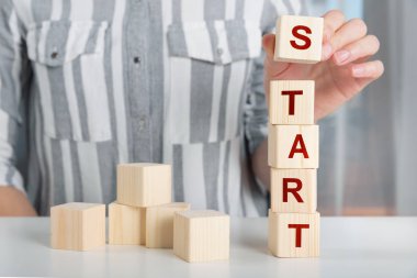 El ahşap küp blok Start Up kelimelerle ta koyarak kadın