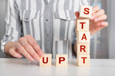 El ahşap küp blok Start Up kelimelerle ta koyarak kadın