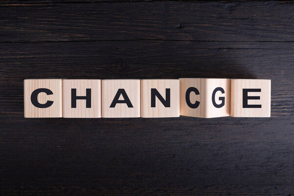 Wooden cube flip with word "change" to "chance" on wood table, P