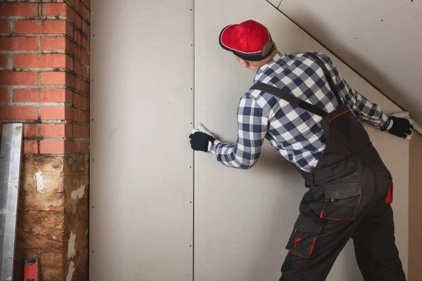 Hombre instalación de placas de yeso hoja a pared para la habitación ático constru — Foto de Stock
