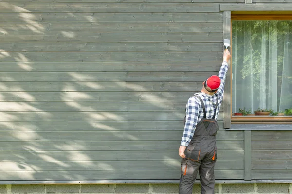 Человек рабочий покраски деревянной стены дома наружной кистью — стоковое фото