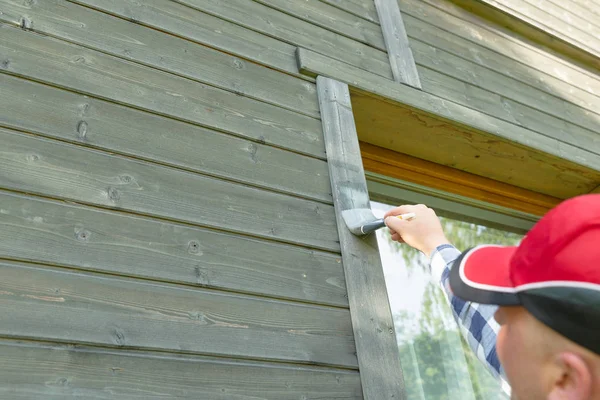 Hombre trabajador pintura madera casa exterior pared con pincel a — Foto de Stock