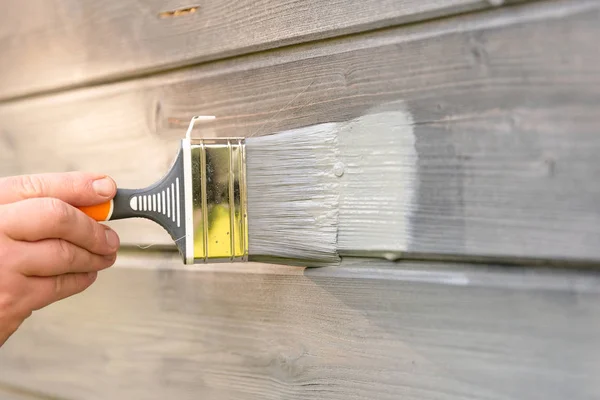 Kvinna arbetar målning trä hus yttervägg med pensel — Stockfoto