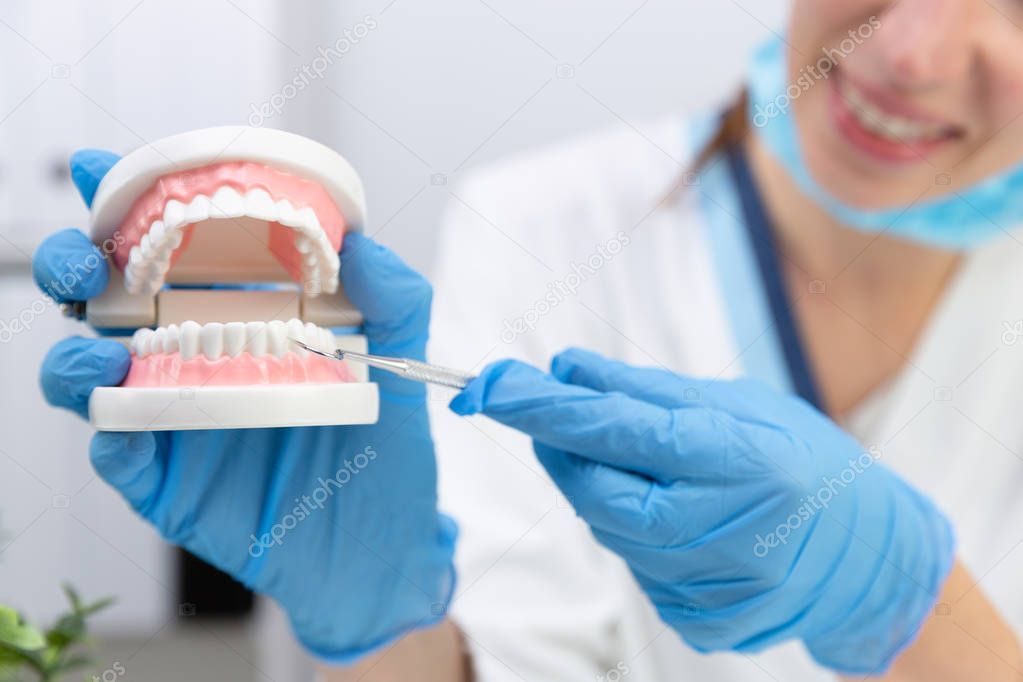 Female dentist holding professional stomatology tool and pointin