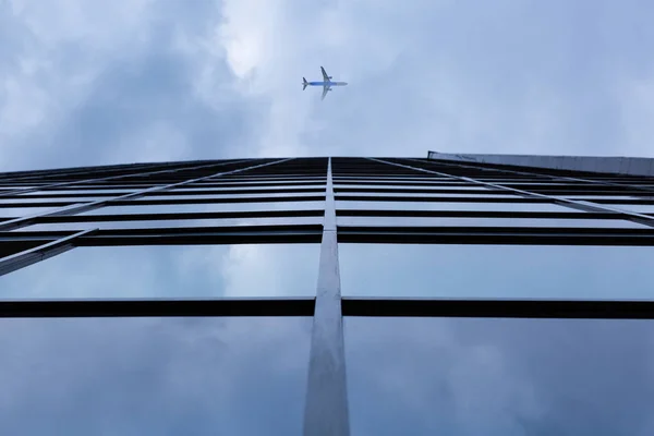 Самолет пролетает над зданием современной архитектуры — стоковое фото