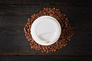 Koyu ahşap masa üzerinde kahve ve kahve çekirdekleri Kağıt fincan. Iyi 