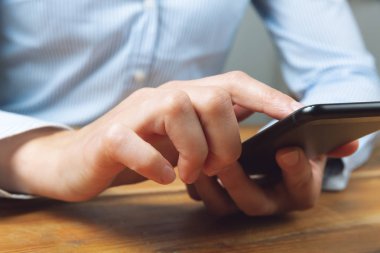 Cep telefonu kullanan bir kadının elleri. Kadın mesajlaşıyor, iş yapıyor.