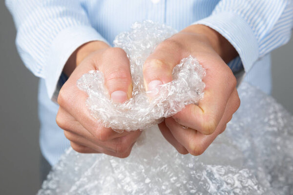Female hands popping the bubbles of bubble wrap. Stress relief, 