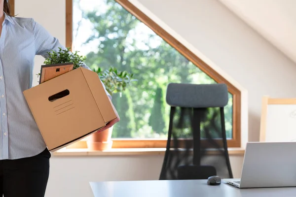 Beautiful business woman carrying a box of office stuff. New work promotion or leaving job concept.