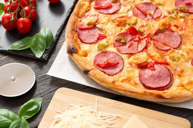 Lezzetli malzemeli sıcak pizza ve siyah desenli bıçaklı pizza.