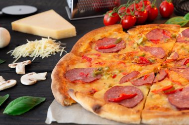 Malzemeli lezzetli sıcak pizza ve siyah desenli bıçaklı pizza. Üst görünüm