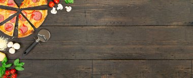 Malzemeli lezzetli sıcak pizza ve siyah desenli bıçaklı pizza. Üst görünüm