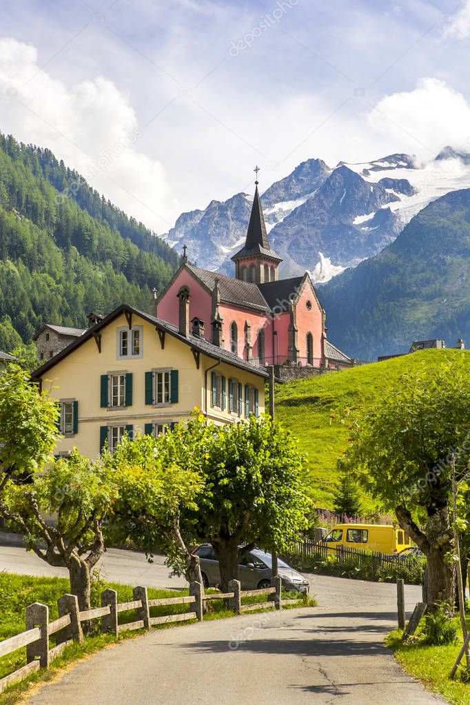 Church and house on the road and mountains in the Alps