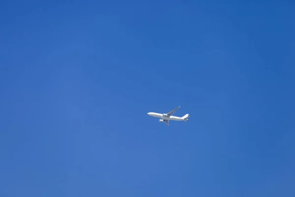 はるかに超える深い青色の空を飛んでいる飛行機 — ストック写真