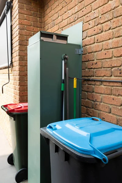 Residential general waste & recycle bins beside hot water service.