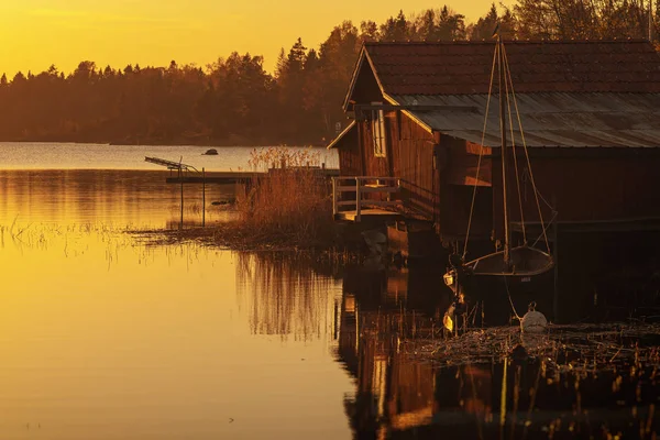 老式的木制小船房子在红色与一条老小船在黄色阳光旁边停泊 — 图库照片