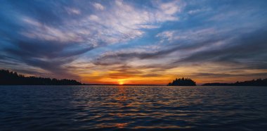 Günbatımı panorama bir adalar kıyısında güzel canlı koyu renklerde. İsveç, Roslagen