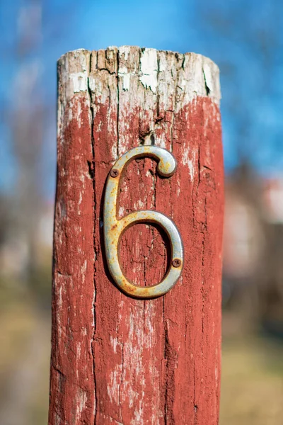 Rusty número seis en un poste de madera rojo en la entrada de un hous — Foto de Stock