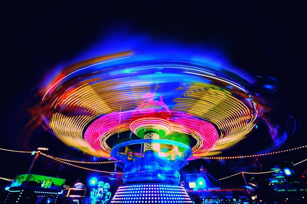 Carosuell colorido brilhante em cores de néon em movimento em uma feira de diversão — Fotografia de Stock