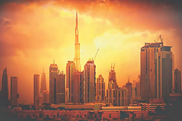 DUBAI, Emiratos Árabes Unidos - 19 ENE 2019: Construcción en el centro de Dubái con Burj Khalifa tocando el cielo naranja de la noche —  Fotos de Stock