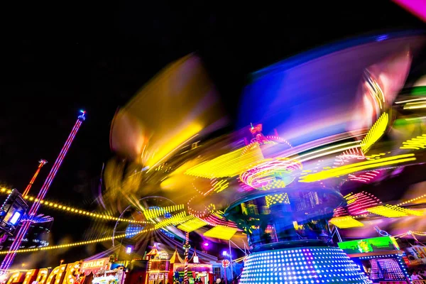 Carosuell colorido brilhante em cores de néon em movimento em uma feira de diversão — Fotografia de Stock