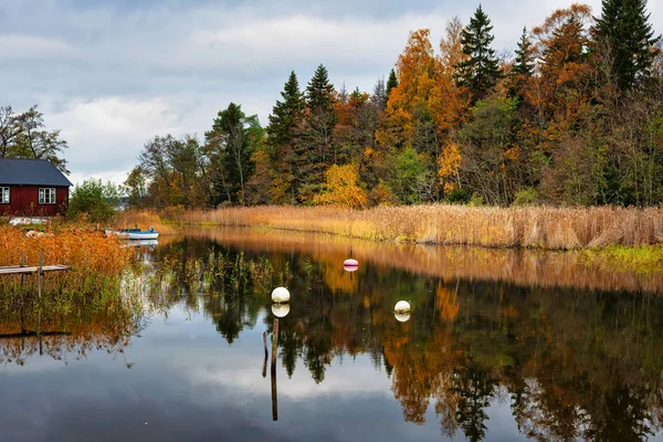 Boathouse na costa em cores de outono vividi, refletindo água — Fotografia de Stock