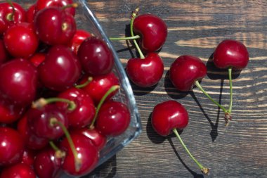 olgun kiraz meyveleri koyu ahşap arka plan üzerinde cam vazoda