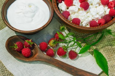 çilek süzme peynir ekşi krema bir dokuma kumaş üzerine bir çömlek içinde ahududu şube