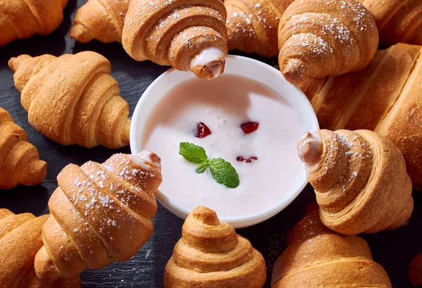 mini croissants are served with yogurt on a black background